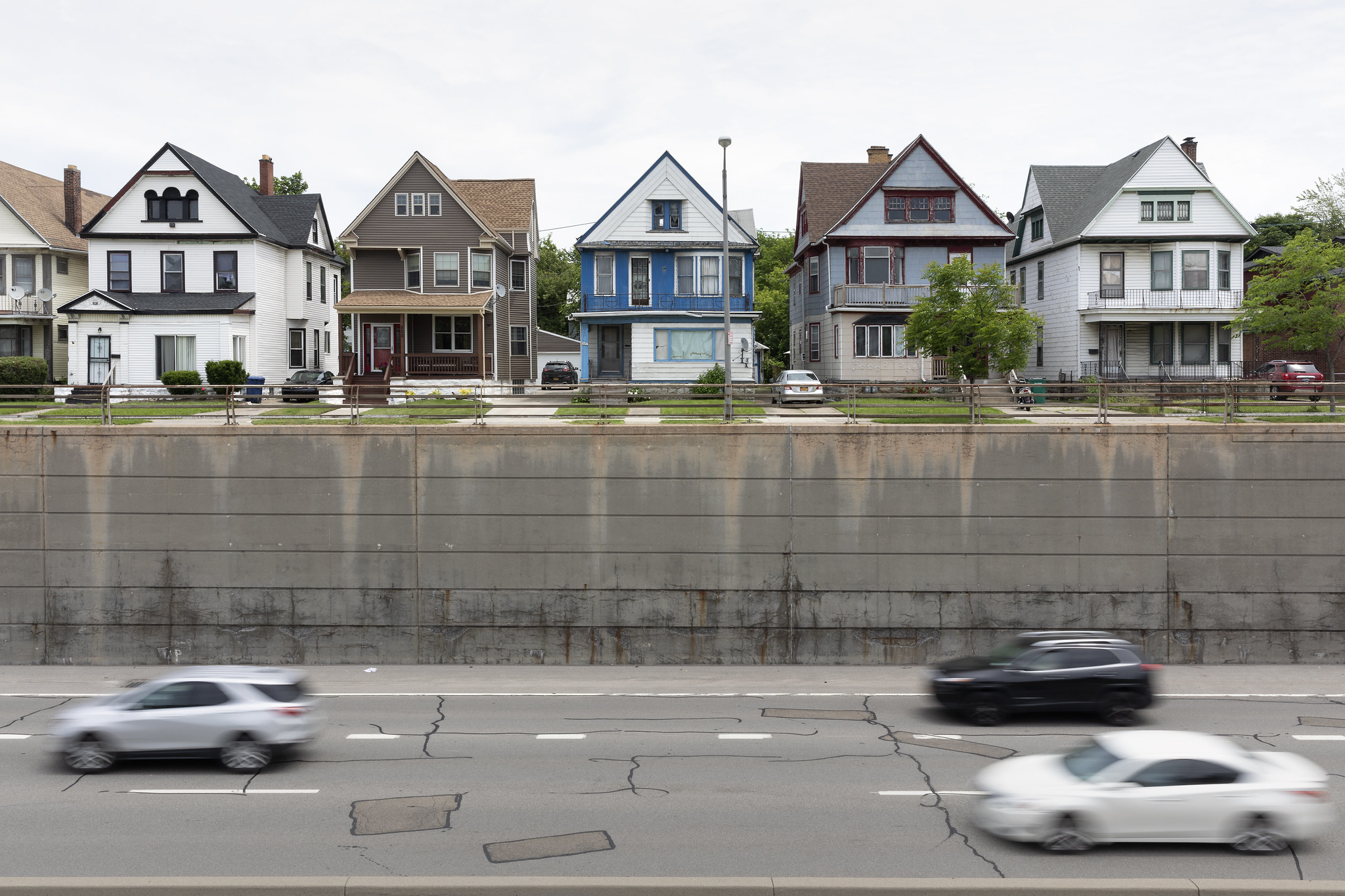 Cars traveling on New York State Route 33, with houses above
