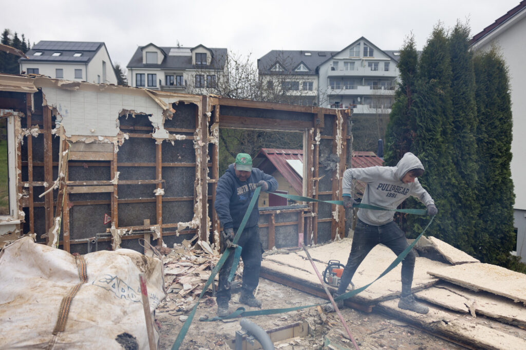 Two men in work clothes demolishing a building in Luxembourg.