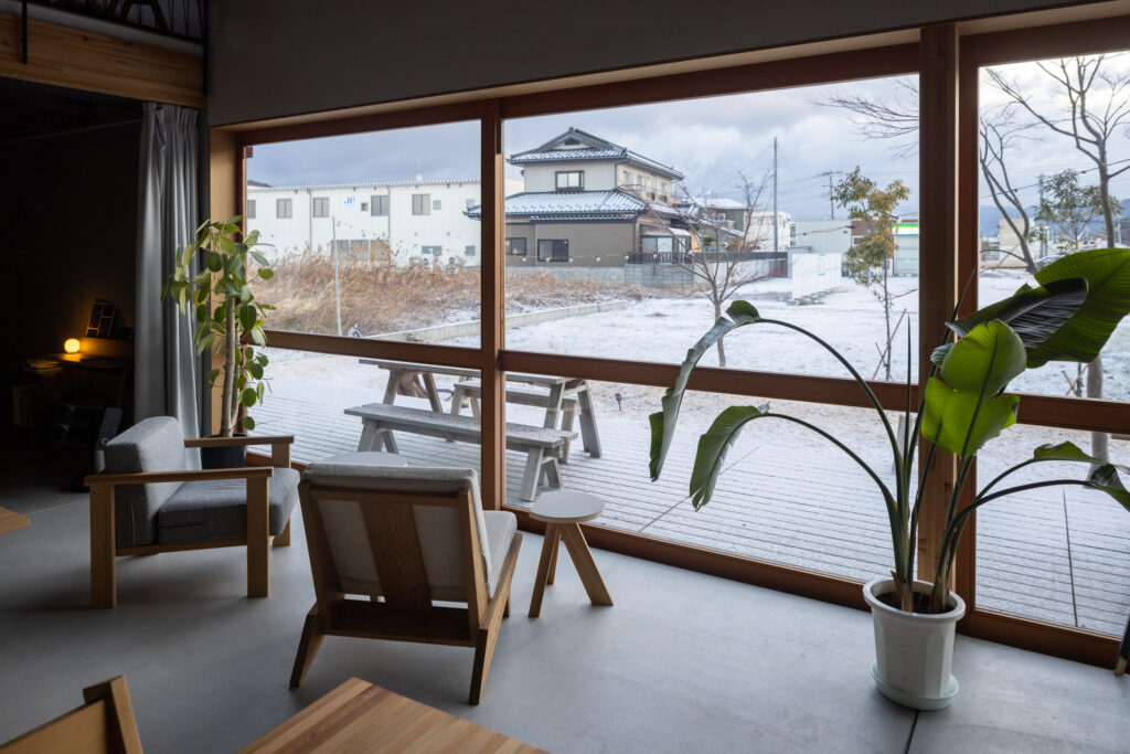 A contemporary room overlooking a snowy landscape in the Ishinomaki Laboratory Home Base.