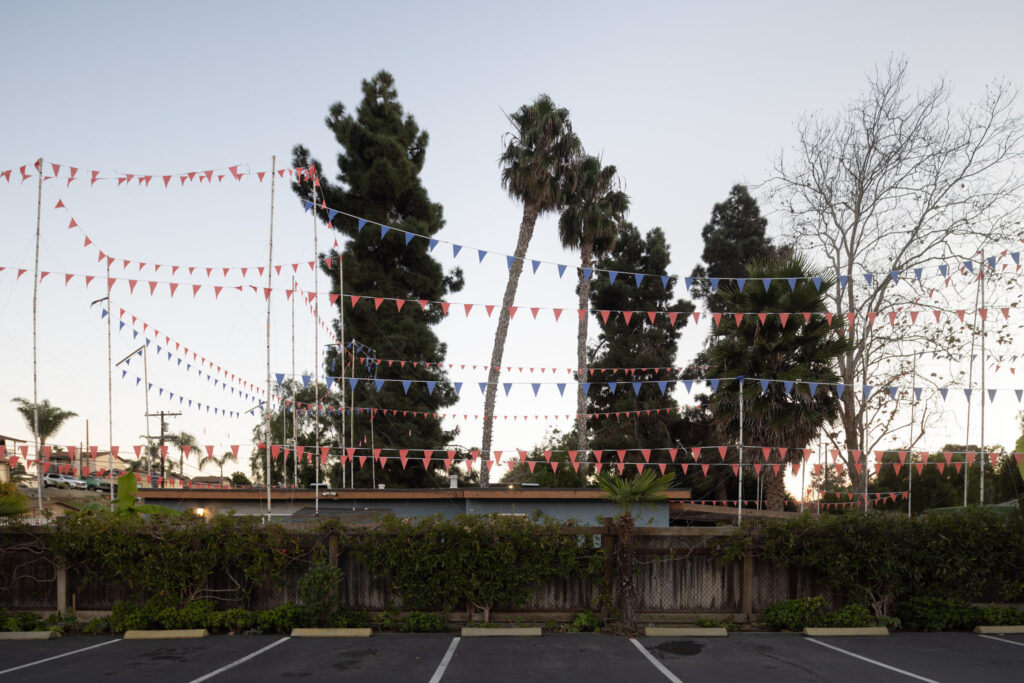 A photograph of flags strung between white poles, illustrating the shape of a proposed building.