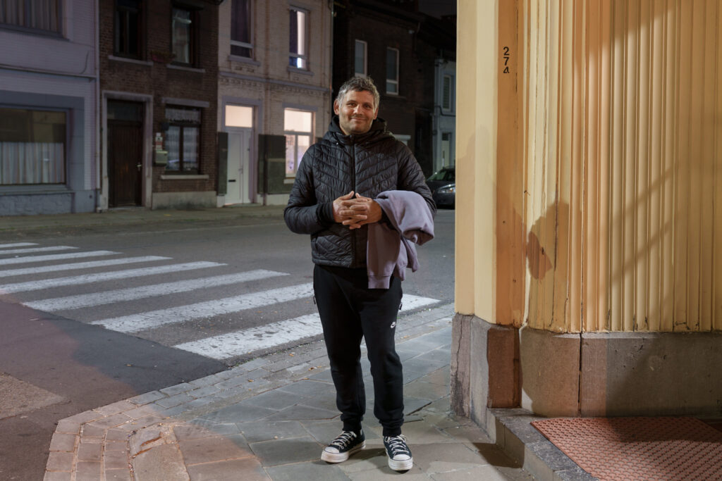A portrait of a man on a street corner at night.