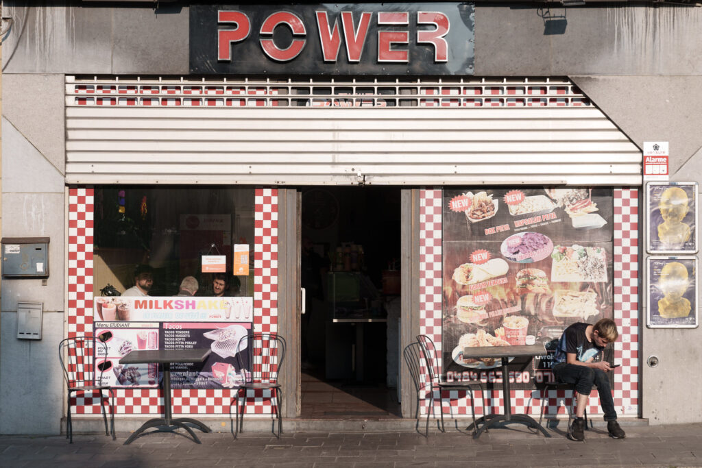 A man sits outside a cafe called POWER.