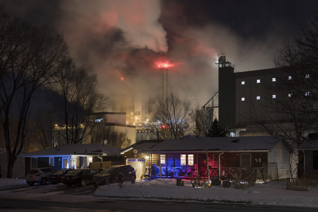A house with a factory behind it, at night.