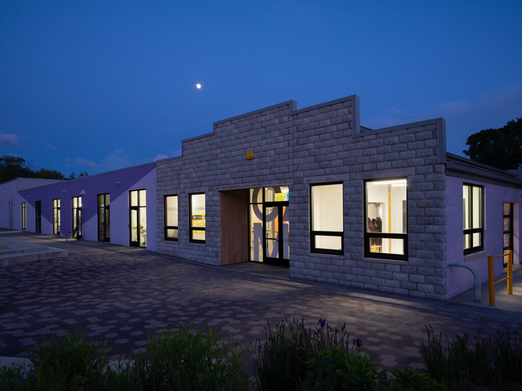 The varied facade of the CAMi museum glows with the moon behind it.